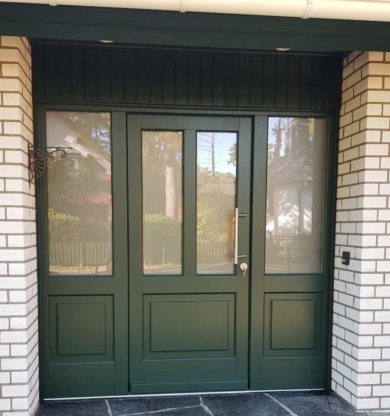 Eine grüne Tür mit einer weißen Backsteinmauer dahinter