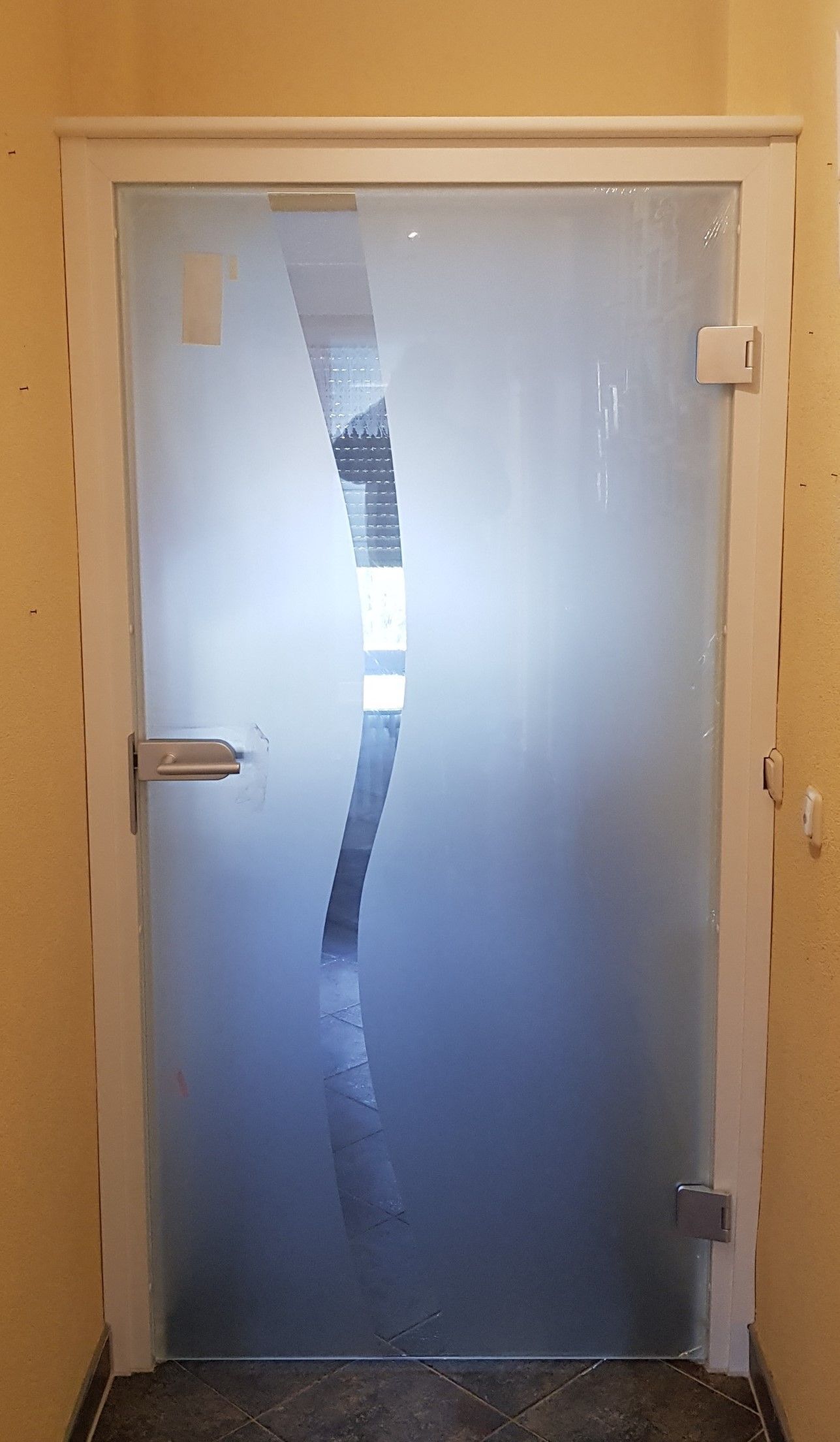 In einem Flur befindet sich eine Milchglastür mit weißem Rahmen.