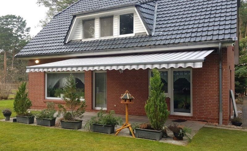 Ein Backsteinhaus mit einer weißen Markise auf der Veranda.