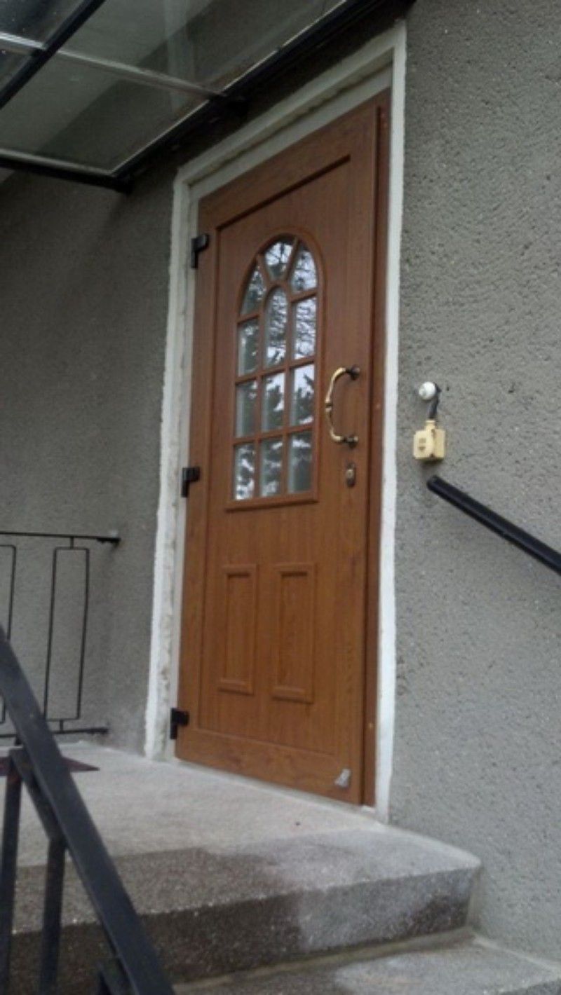 Eine Holztür an einem Gebäude, zu der eine Treppe hinaufführt