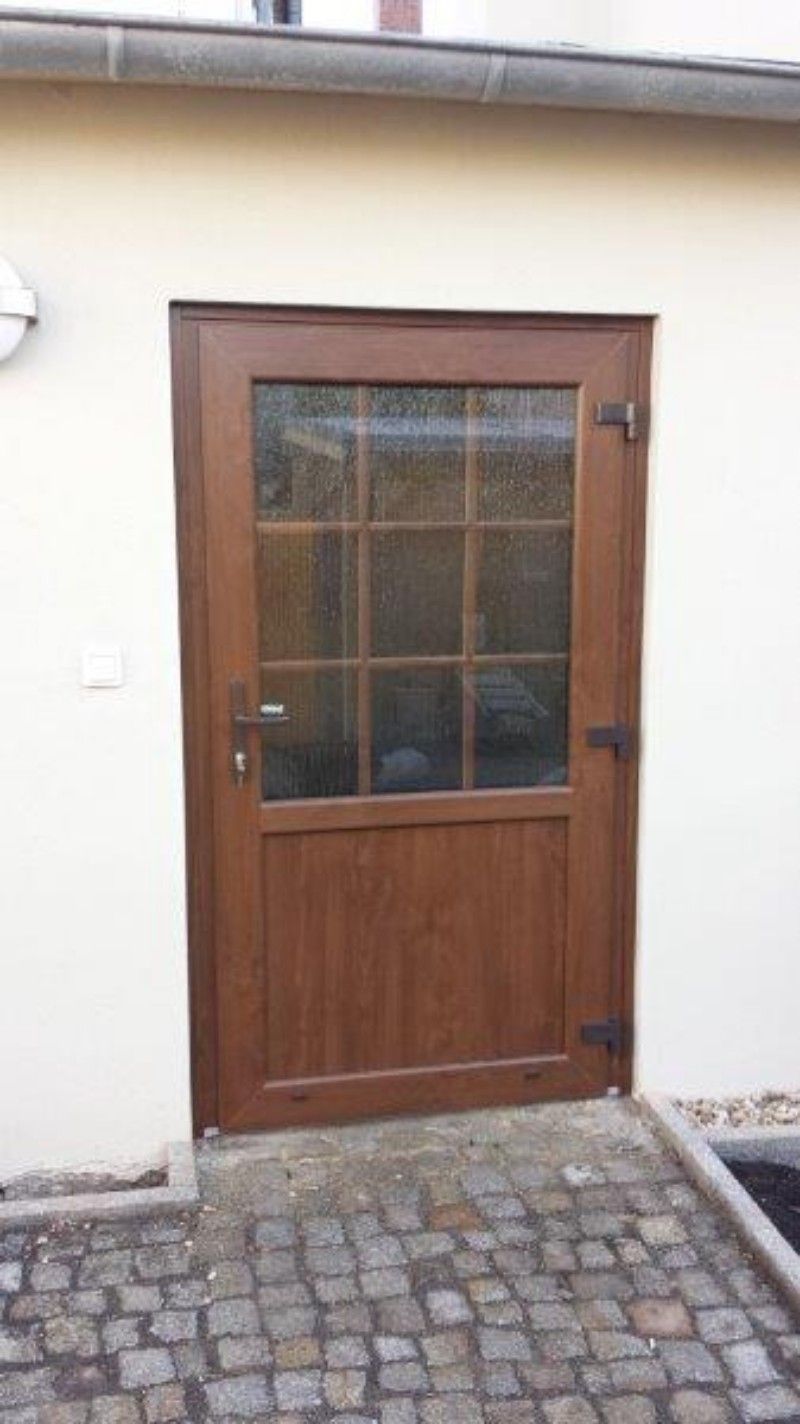 An der Seite eines Gebäudes befindet sich eine Holztür mit einem Glasfenster.