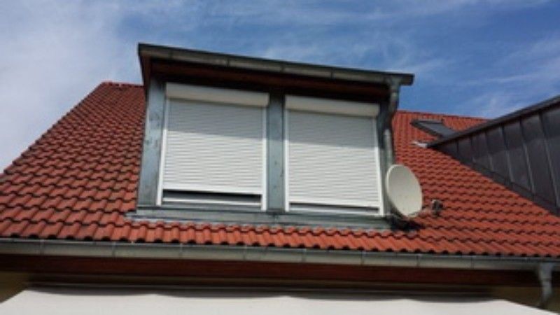 Ein rotes Ziegeldach mit einem Fenster mit Fensterläden