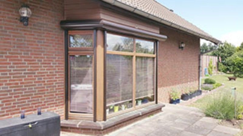Ein Backsteinhaus mit großem Fenster und davor liegender Terrasse.