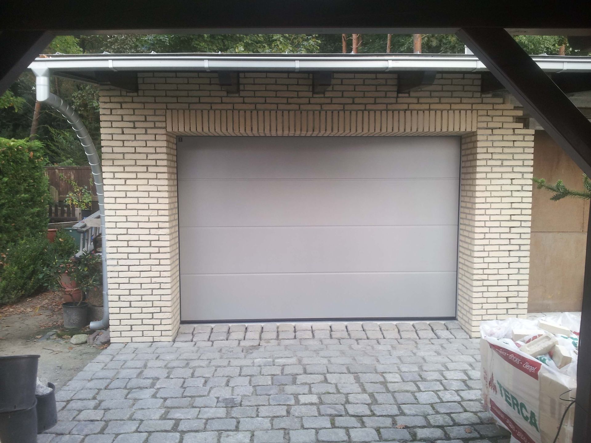 Eine gemauerte Garage mit einem weißen Garagentor