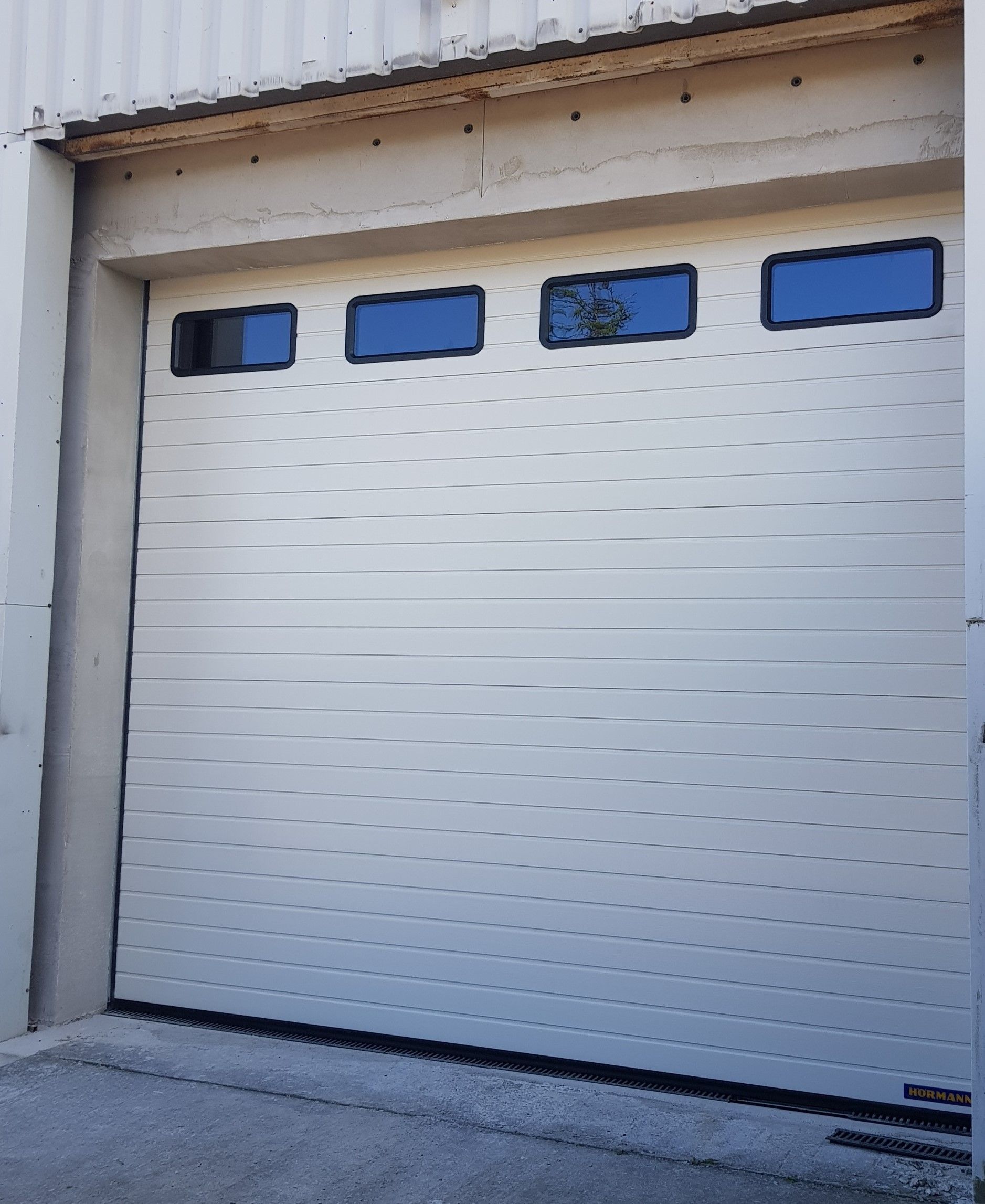 Ein weißes Garagentor mit blauen Fenstern