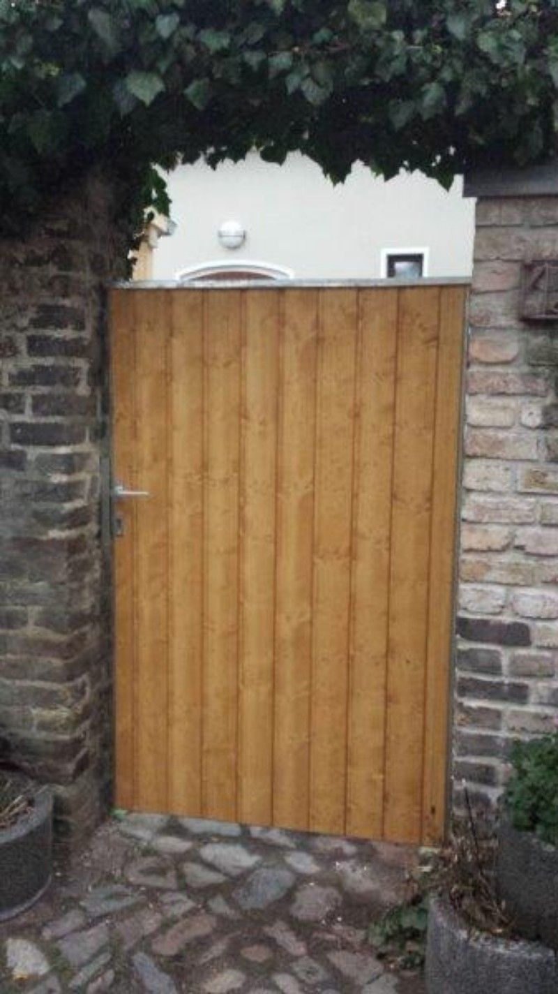 An einer Backsteinmauer ist ein Holztor befestigt.