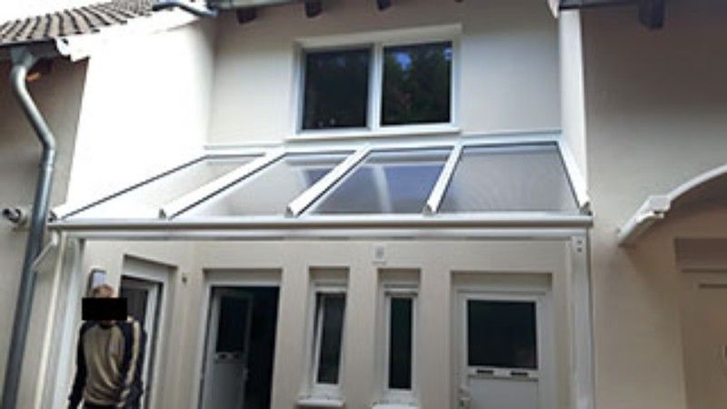 Ein Mann steht vor einem Haus mit einem Vordach über der Tür.