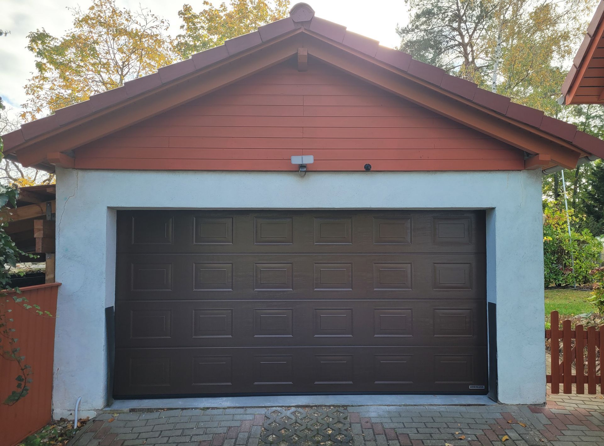 Eine Garage mit brauner Tür und rotem Dach
