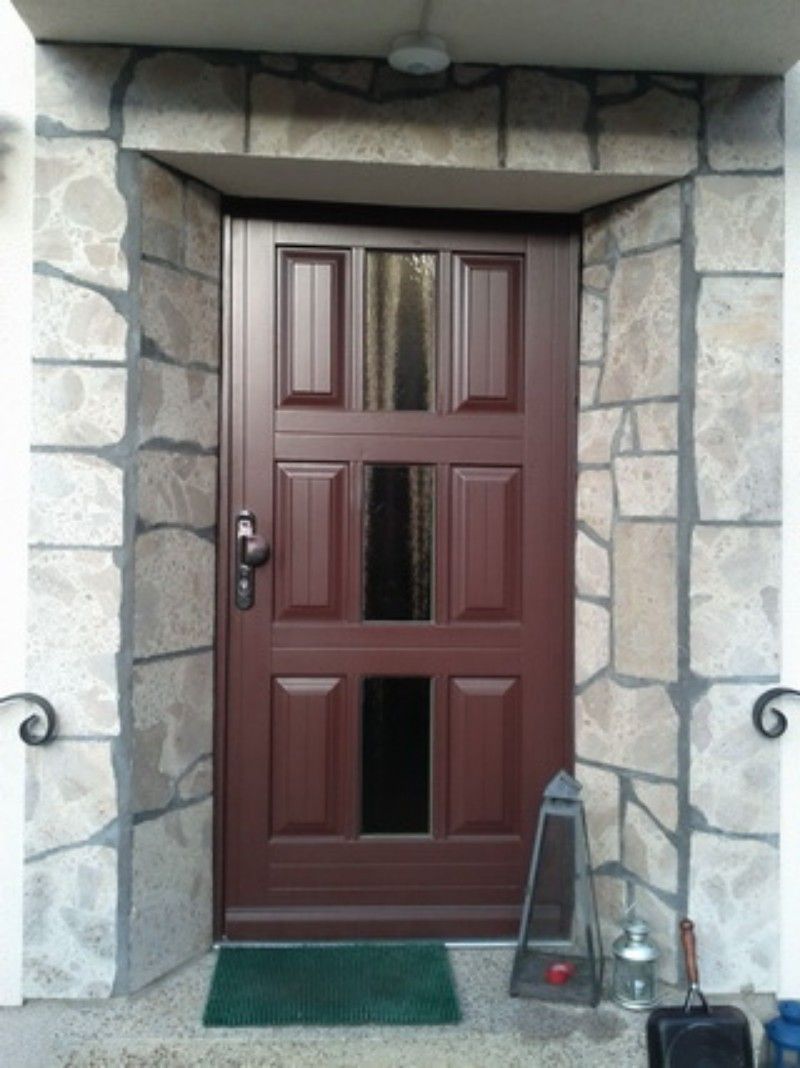 Eine braune Tür mit einer Steinmauer dahinter