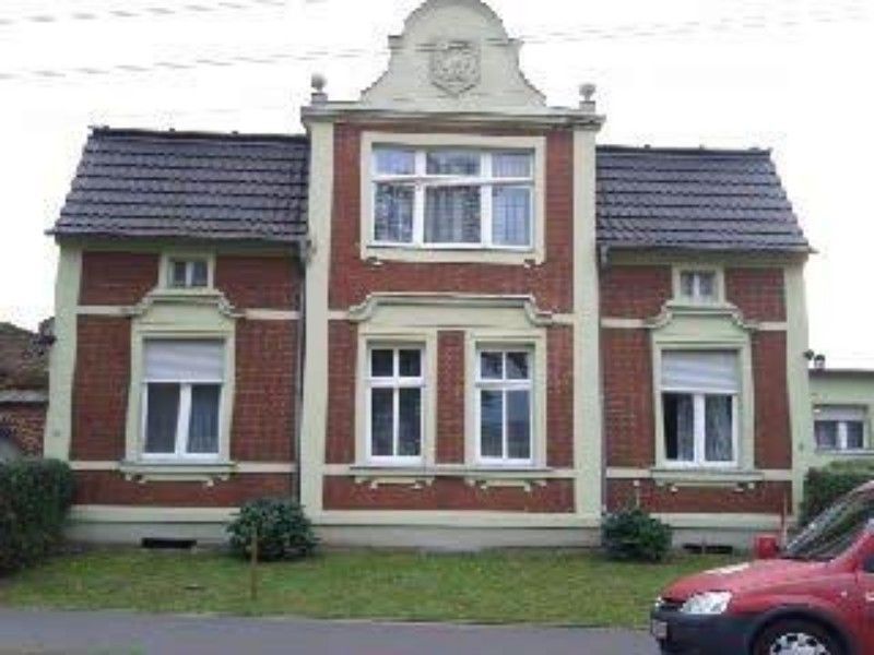 Ein rotes Auto steht vor einem großen Backsteingebäude.