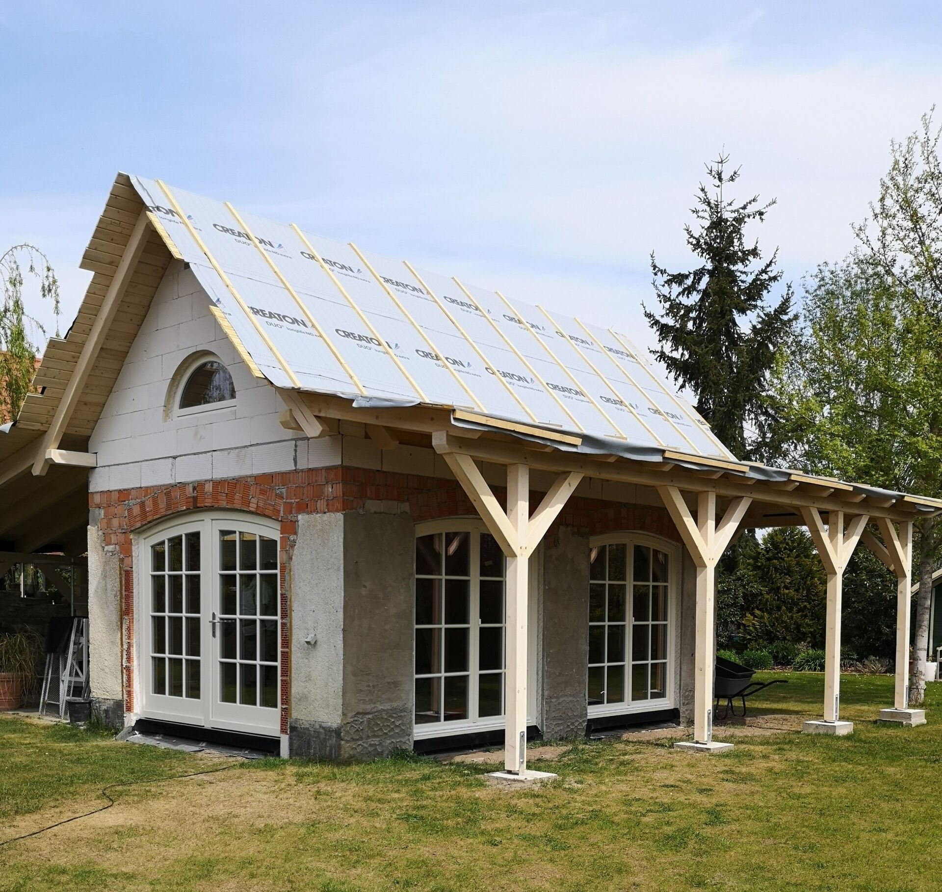 Ein kleines Haus mit einem Holzdach und vielen Fenstern