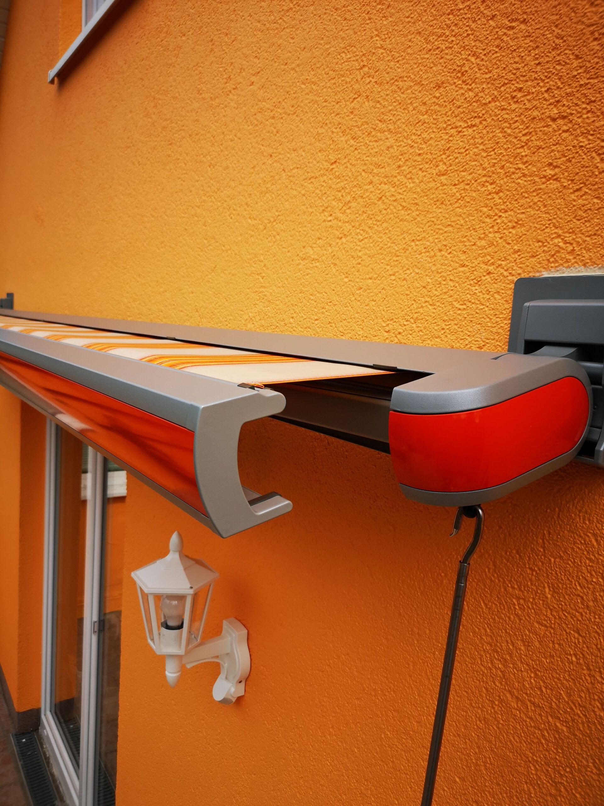 An der Seite eines orangefarbenen Gebäudes ist eine rote Markise angebracht