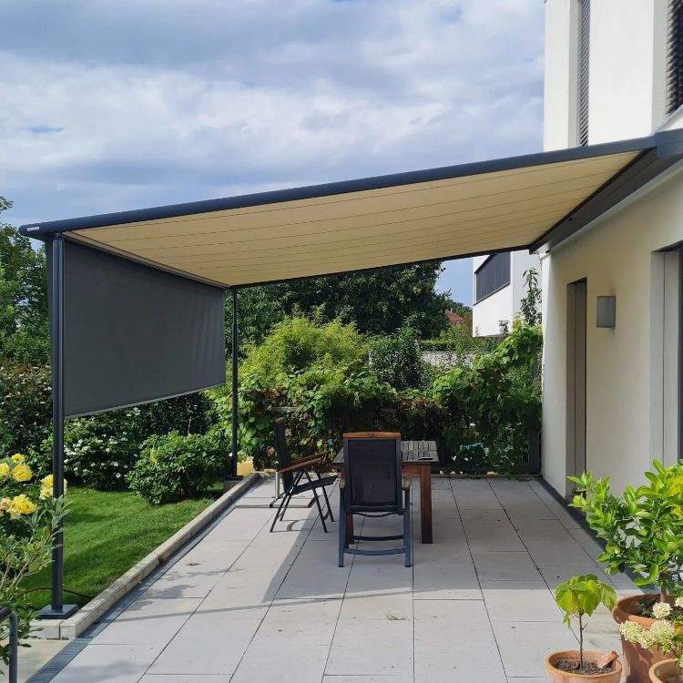 Eine Terrasse mit Tisch und Stühlen unter einem Baldachin