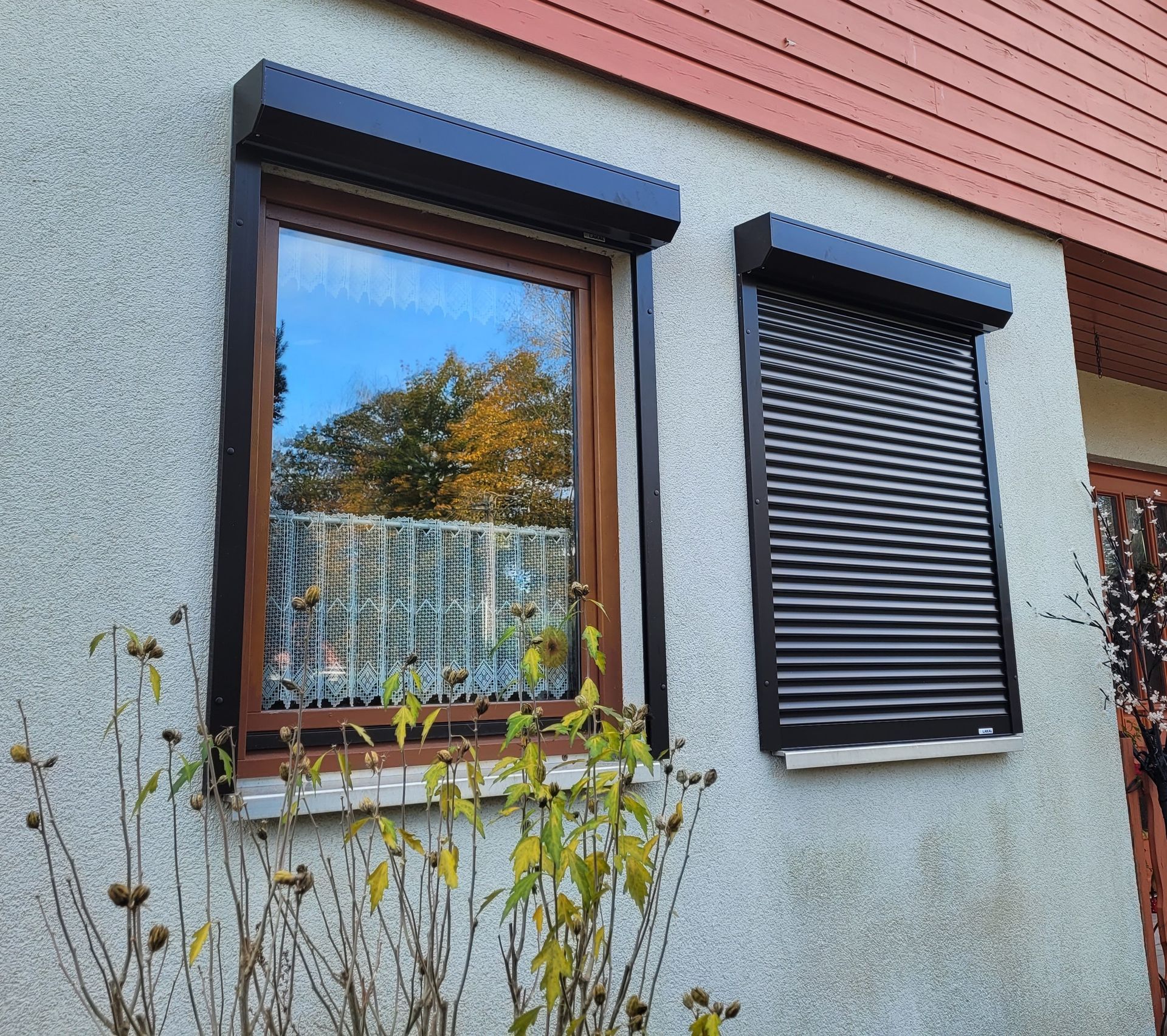 Zwei Fenster an der Seite eines Hauses mit schwarzen Fensterläden