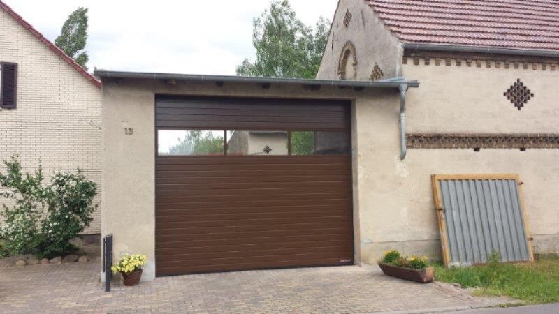 Eine Garage mit einer braunen Tür steht neben einem Haus