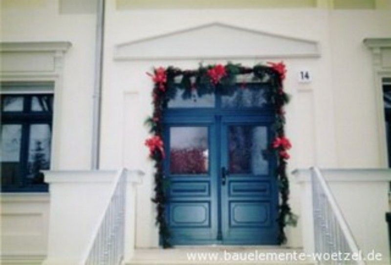 Eine blaue Tür ist mit roten Blumen und Grün dekoriert