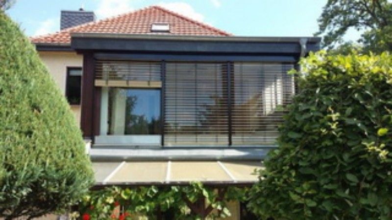 Ein Haus mit einem großen Fenster und einem Dach, das von Bäumen umgeben ist.