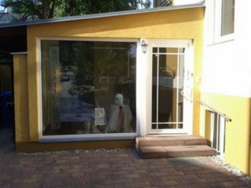 Ein gelbes Gebäude mit einer weißen Tür und einem großen Fenster