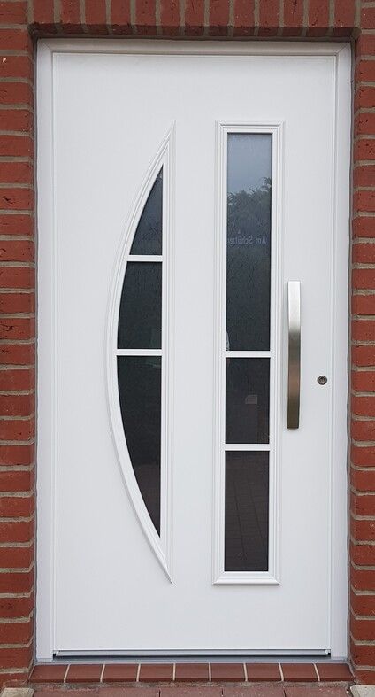 An einer Ziegelwand hängt eine weiße Tür mit einem Edelstahlgriff.