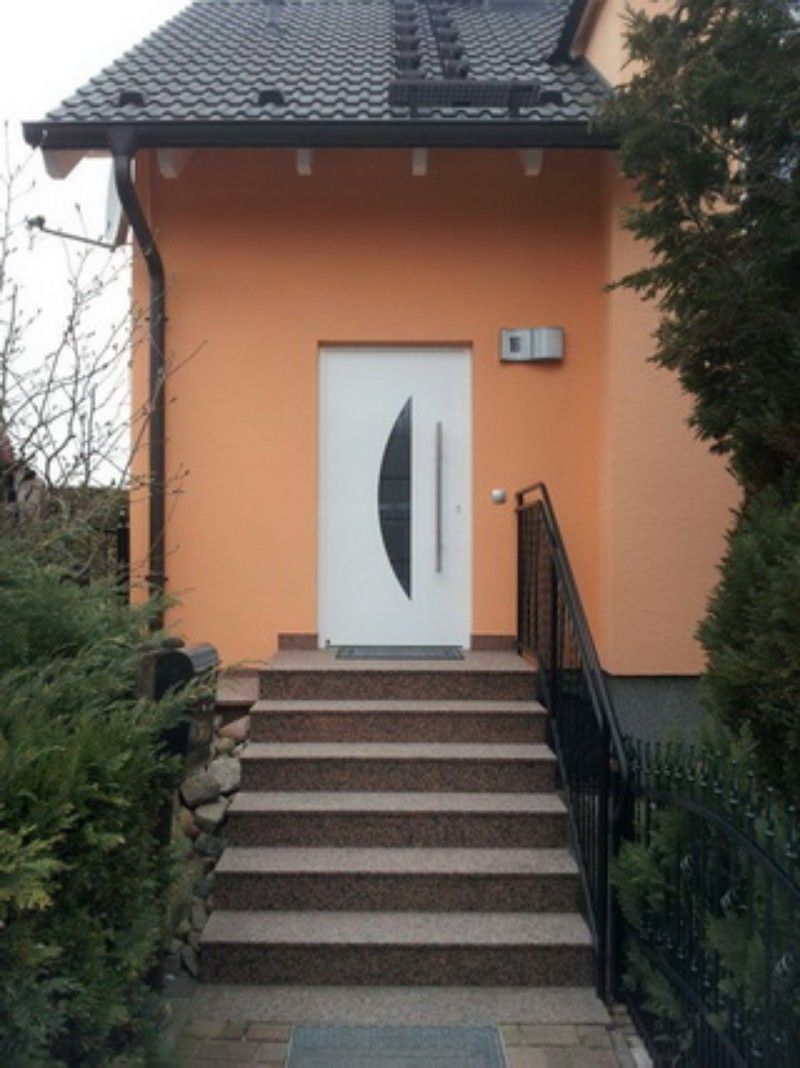 Ein orangefarbenes Haus mit einer weißen Tür und Treppe