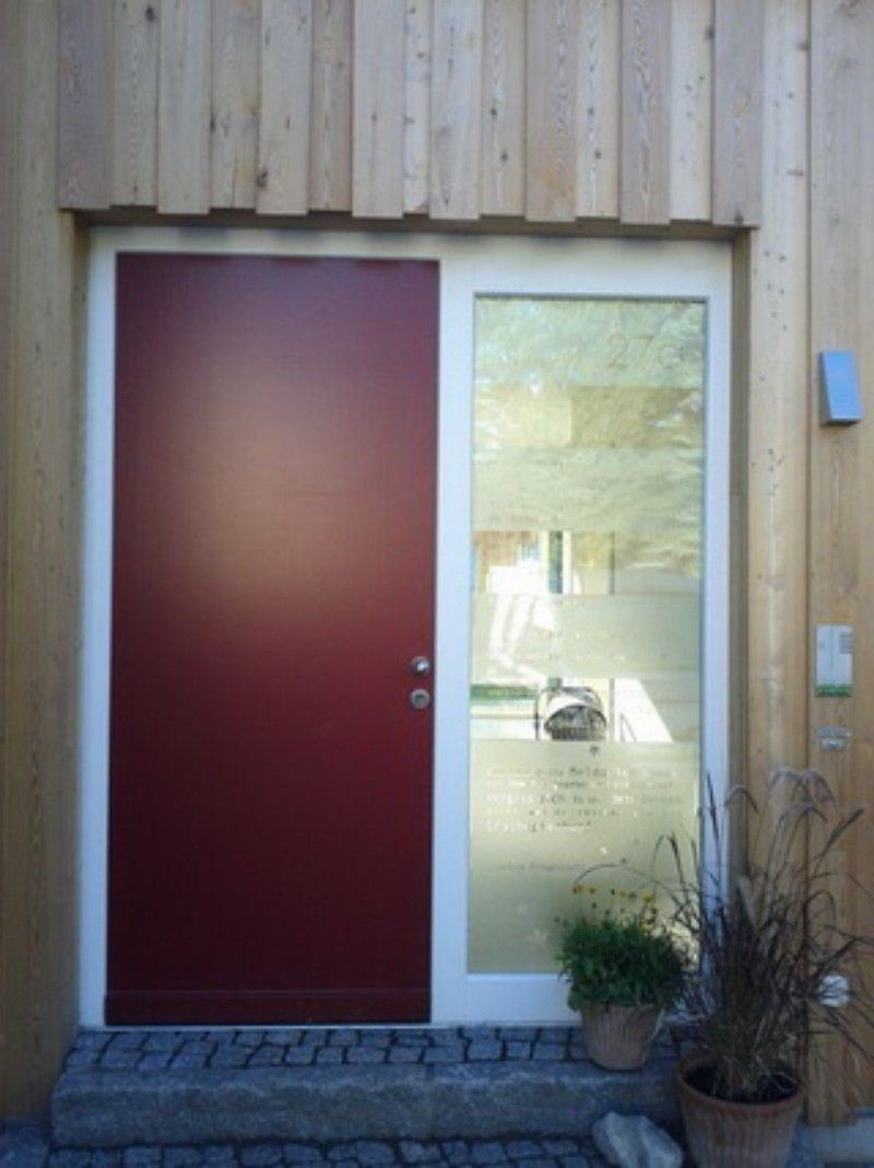Eine rote Tür mit weißem Rahmen und einer Glastür