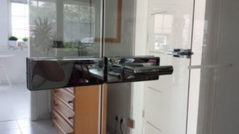 In einem Raum steht eine Glastür mit einem schwarzen Griff offen.