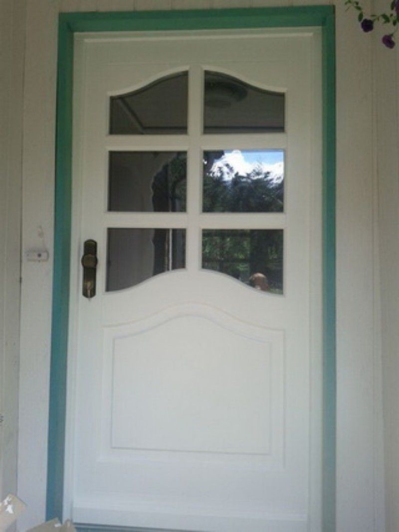 Eine weiße Tür mit grüner Verzierung und einem Fenster