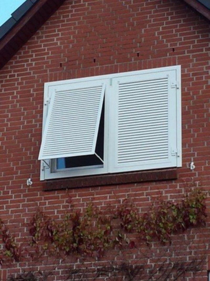 Ein rotes Backsteingebäude mit weißen Fensterläden