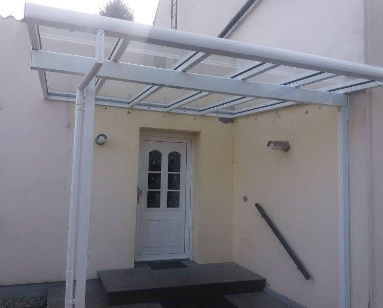 Eine weiße Tür mit einem durchsichtigen Vordach darüber