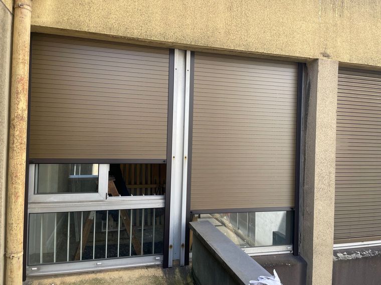 Volets marron sur un bâtiment ocre.