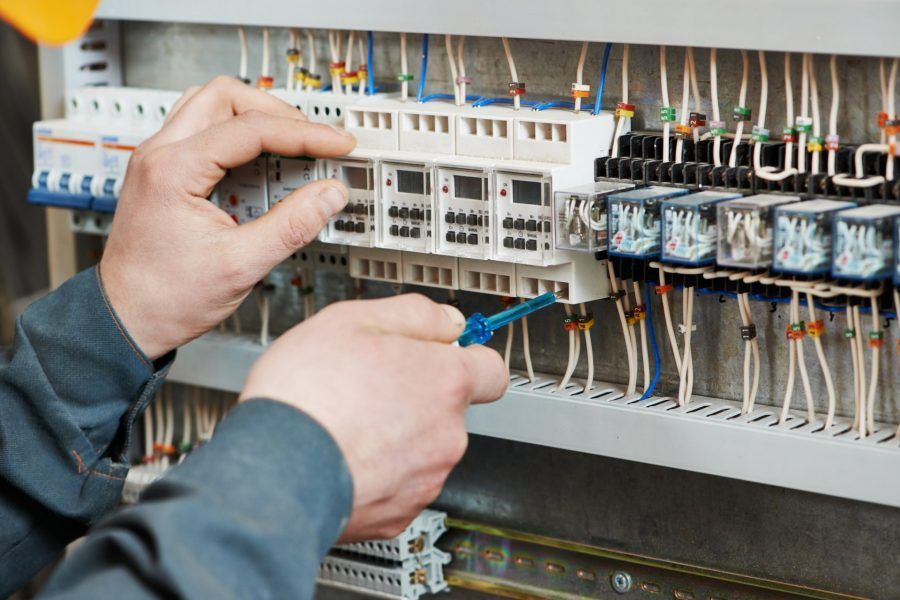 Technicien effectuant le câblage d'un panneau de commande électrique avec des relais et des bornes