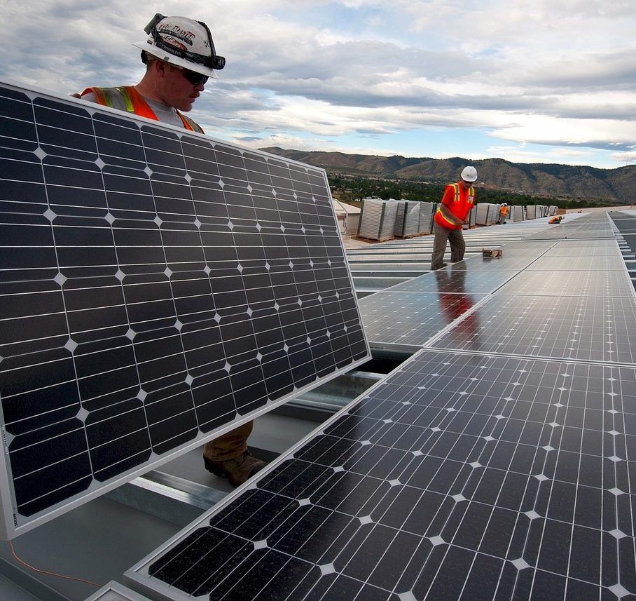 Des ouvriers installent des panneaux solaires sur un toit sous un ciel nuageux