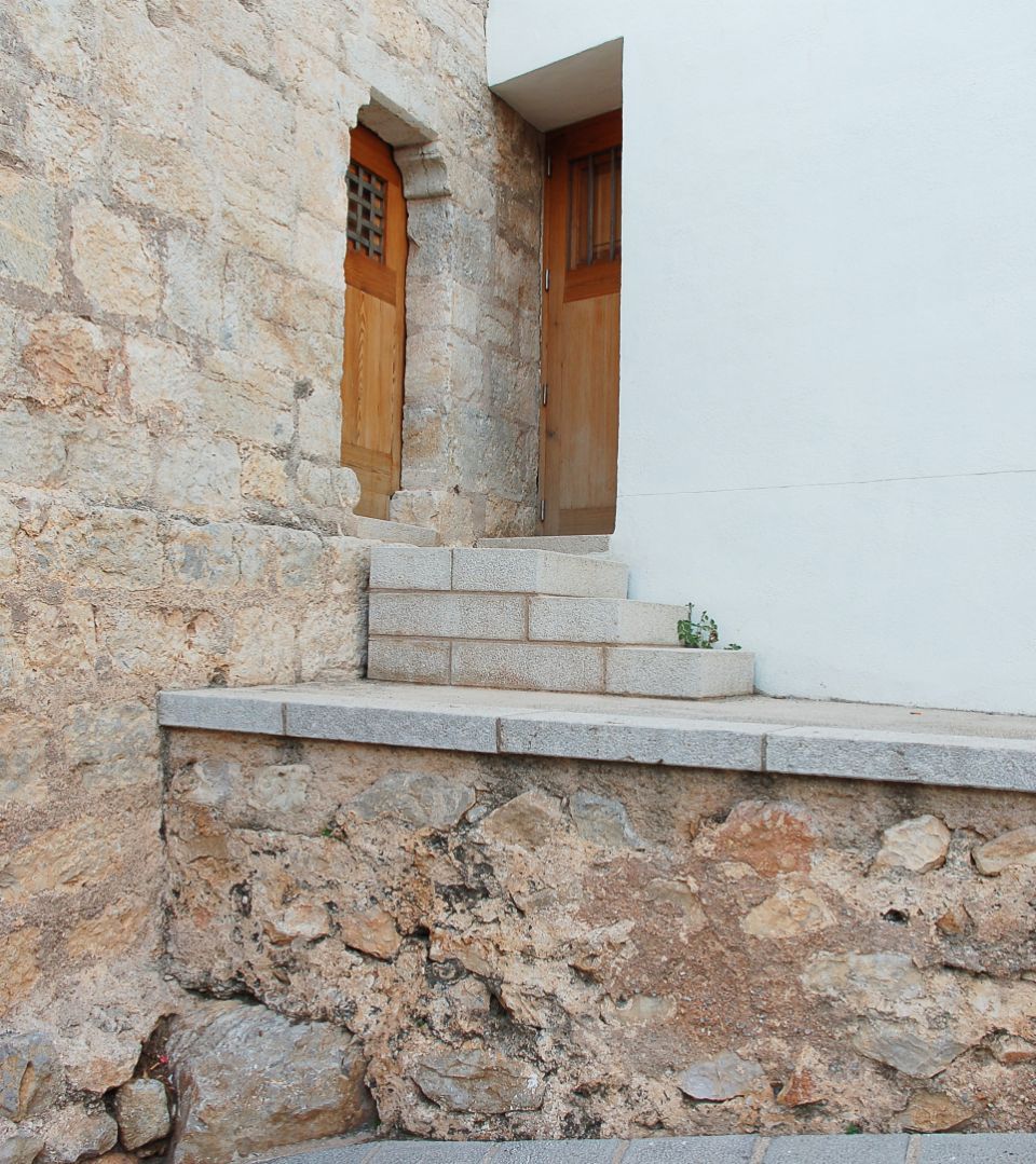 Haus, mit je einer Fassadenseite aus Naturstein und weißem Putz