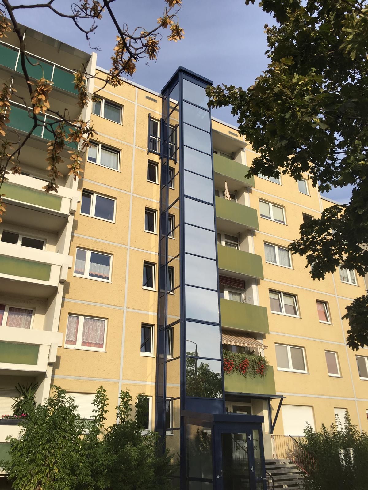 Ein hohes Gebäude mit einem gläsernen Aufzug in der Mitte