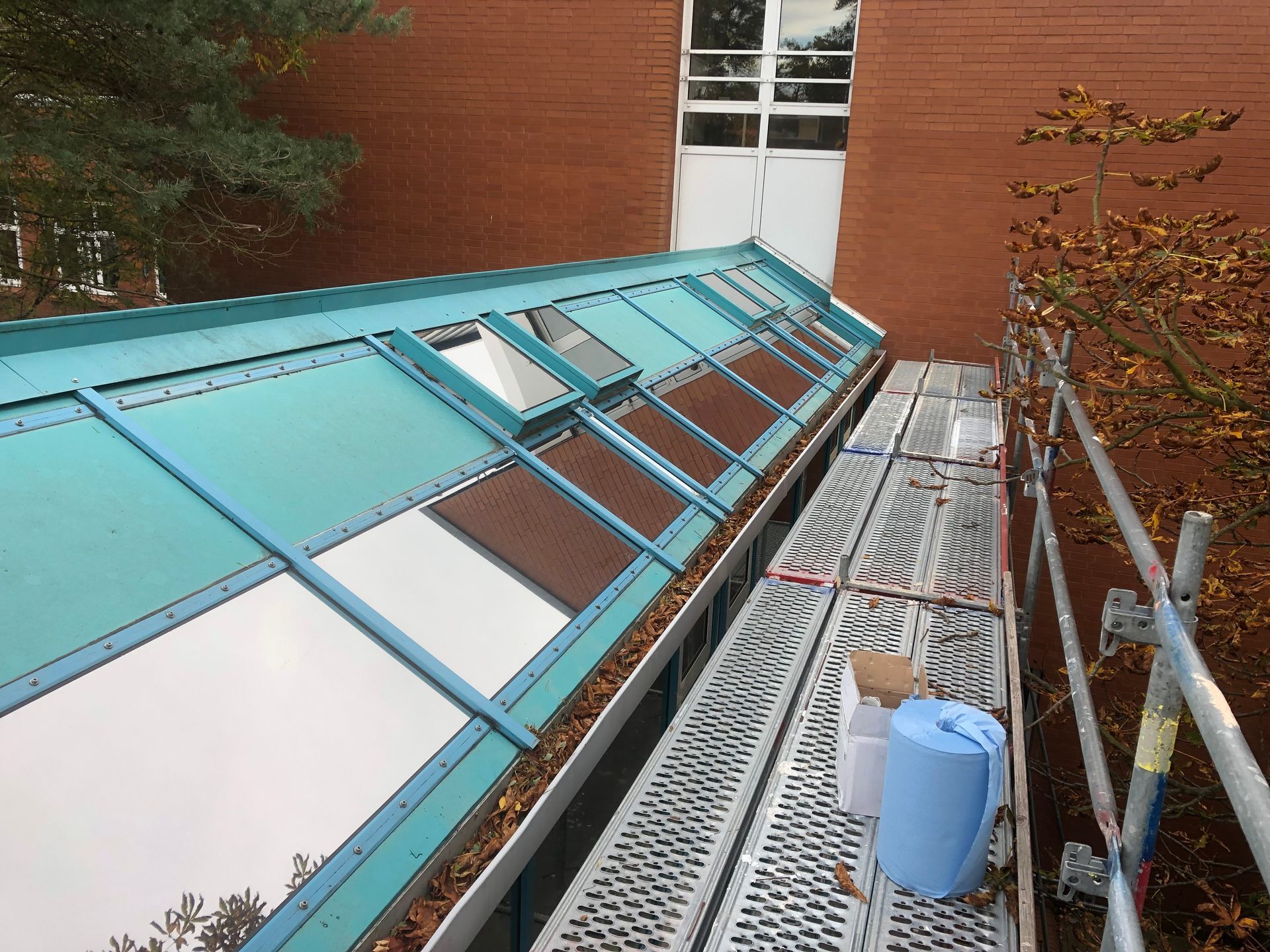 Ein blauer Eimer steht auf einem Gerüst neben einem Gebäude