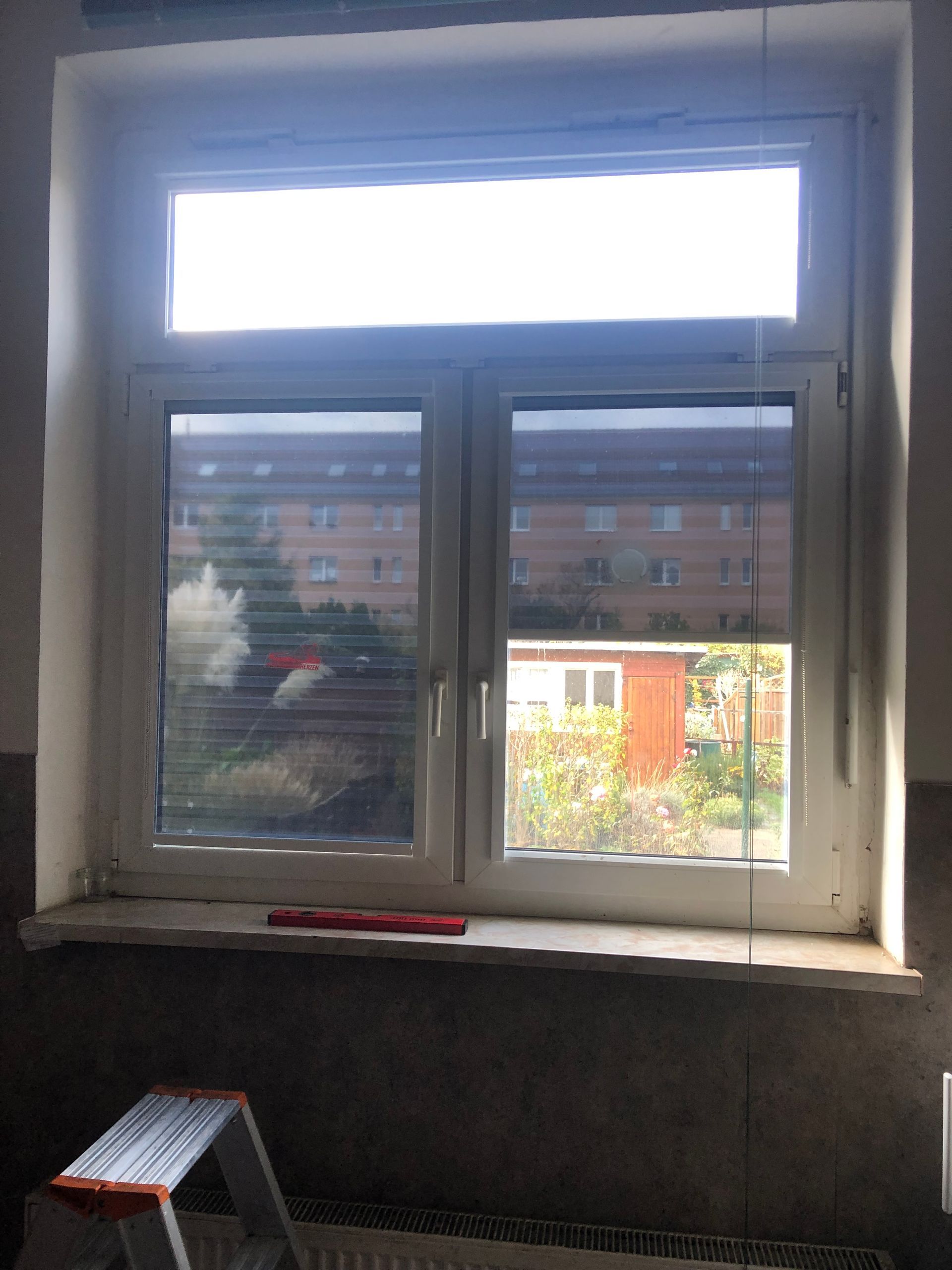 Ein Fenster mit Jalousien und einer Leiter davor