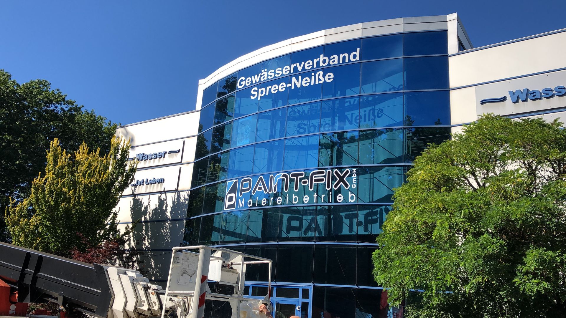 Ein großes Gebäude mit vielen Fenstern und Bäumen davor.