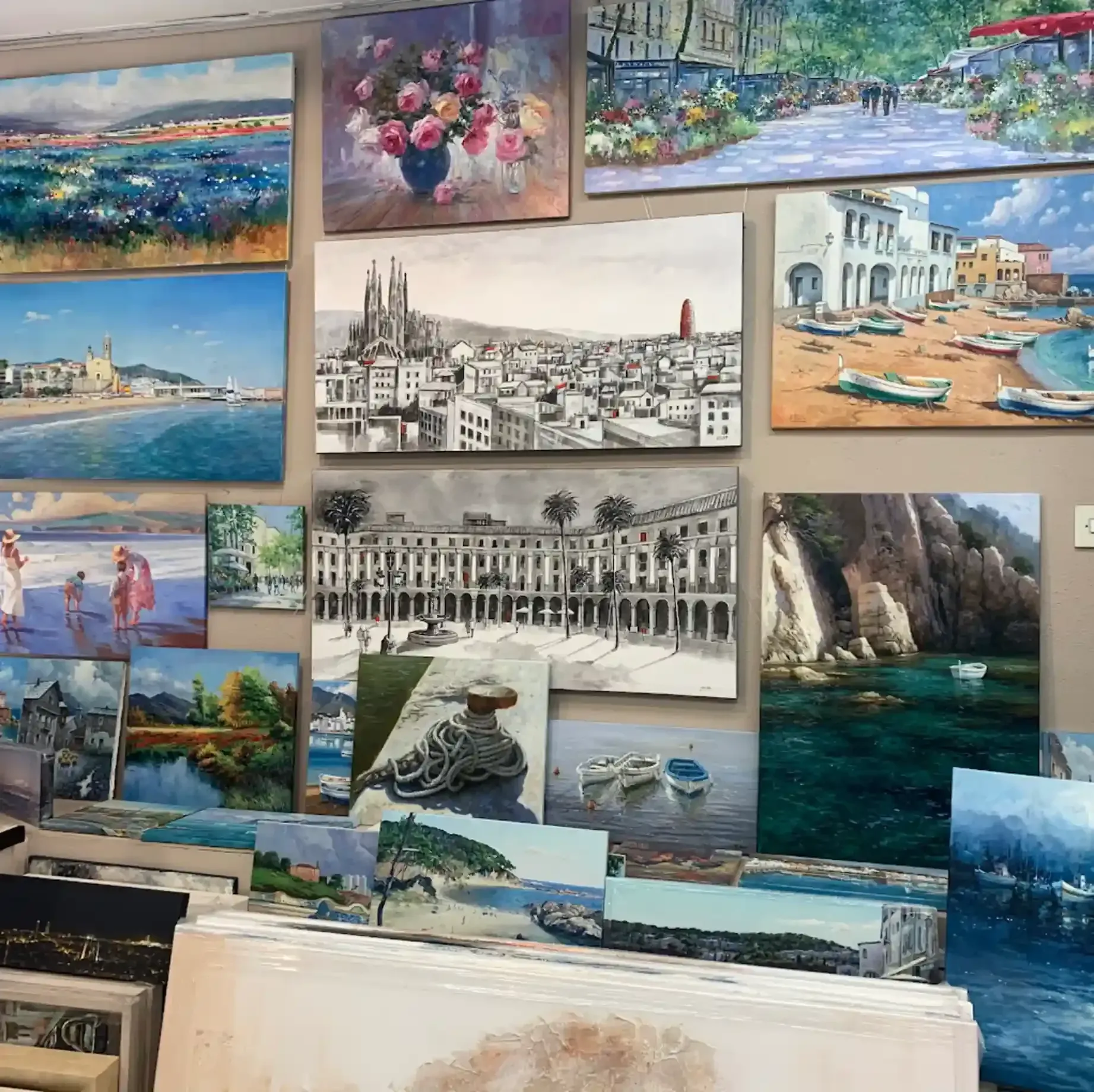 Una colección de diversos cuadros al óleo de paisajes y bodegones expuestos en una pared de una galería de arte.