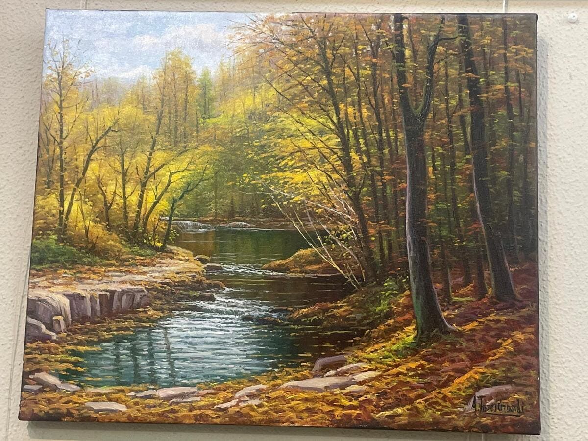 Arroyo otoñal en el bosque con árboles dorados y una pequeña cascada.