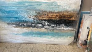 Pintura abstracta con pinceladas horizontales superpuestas de azul, blanco y dorado terroso, que recuerdan a un paisaje costero.