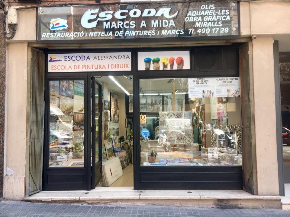 Fachada de Escoda, una tienda especializada en marcos a medida, material de arte y clases de pintura, ubicada en un edificio revestido de piedra.