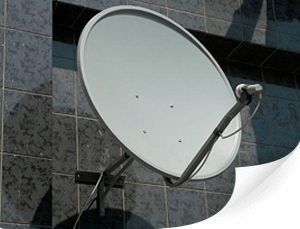 Antena parabólica montada en una pared de azulejos oscuros.