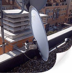 Antenas parabólicas en una azotea, con la ciudad de fondo.