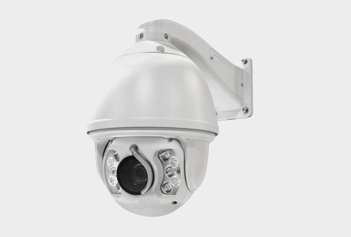 Cámara de seguridad blanca montada sobre un soporte, probablemente en exteriores.