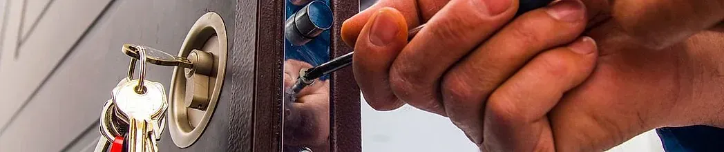 Primer plano de las manos de una persona que utiliza una herramienta para abrir una cerradura de puerta con llaves.