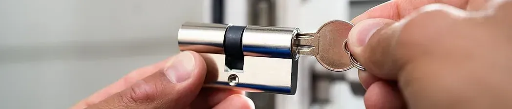 Una mano insertando una llave en una cerradura plateada de una puerta, en el interior.