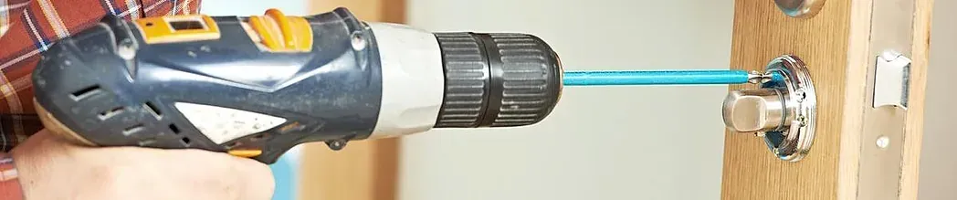 Una persona utiliza un taladro para instalar un componente metálico en una superficie de madera.
