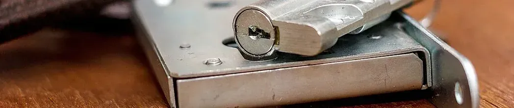 Primer plano de un componente de cerradura de plata sobre una superficie de madera. Se ve parte de la cerradura.