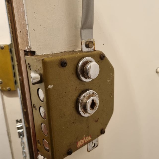 Primer plano de una cerradura de puerta desgastada, con pomo y cerradura plateados.