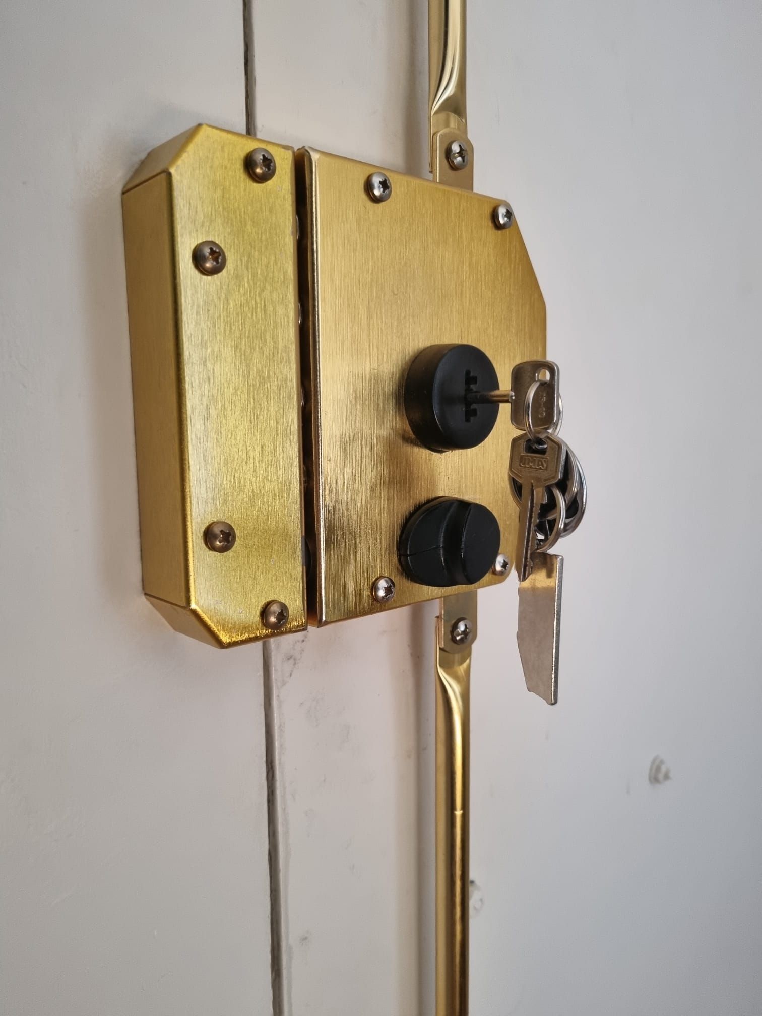 Cerradura de puerta de latón con llave en la cerradura, montada en una puerta blanca.